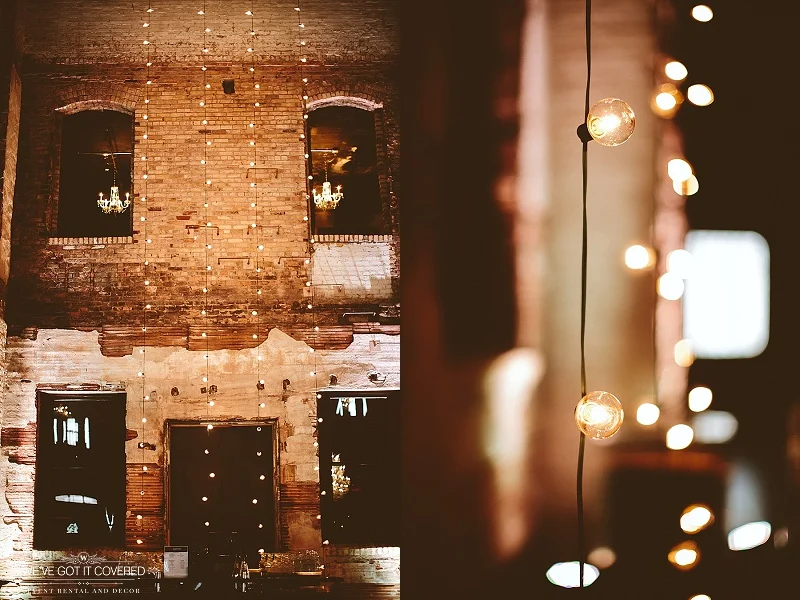 Cafe lights strung down a beautiful brick wall with the accompaniment of a few crystal chandeliers.