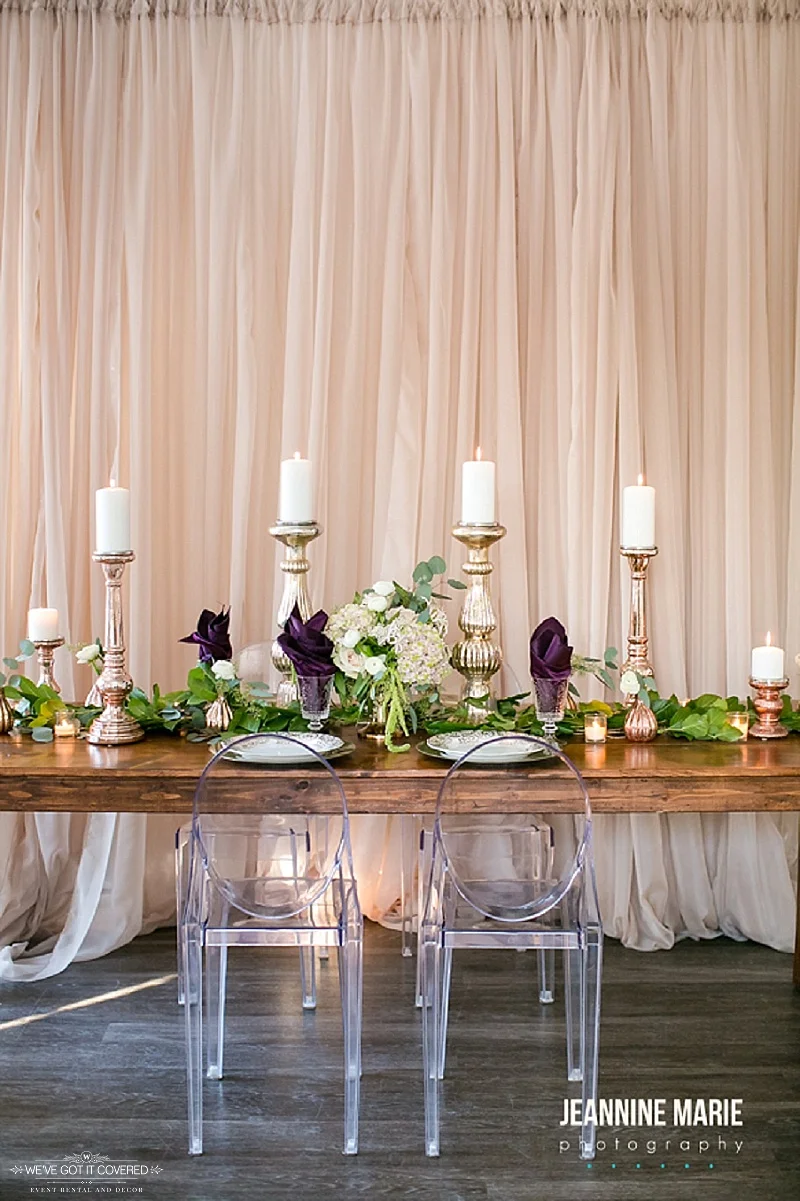 Farm table that has a beautiful taupe backdrop that make greenery and other decor stand out.