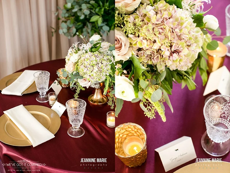 Burgundy linen with gold chargers, crystal cups, floral, and gold candle votive cups