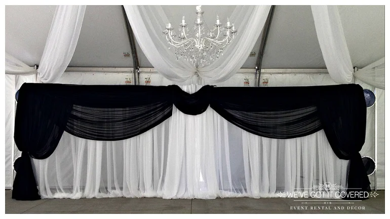black draping hung on a backdrop inside a tent for a Minnesota wedding featuring a crystal chandelier