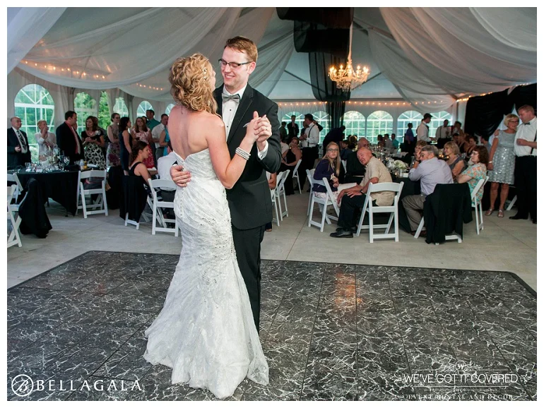 First dance as husband and wife inside a beautiful tent with chandelier lighting and black and white draping throughout