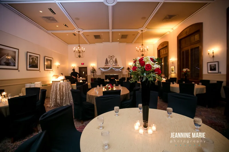 Wedding reception space with black chair covers, gold linens, red flowers and romantic candles