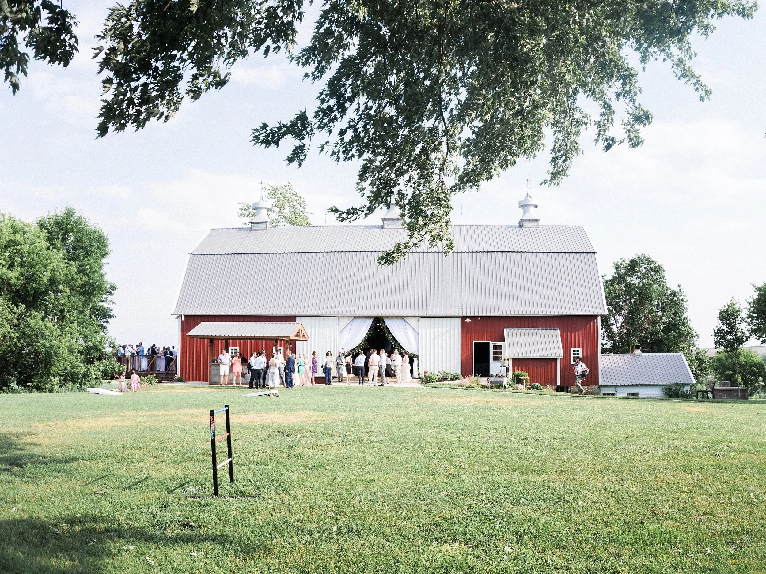 Red barn farm wedding venue with decor rentals including draping the entrance, table linens, table runners, garland and cafe lighting