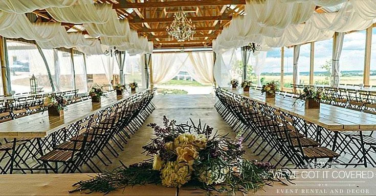 Wedding reception draping in an outside pavilion with flowers in wood boxes for the centerpiece