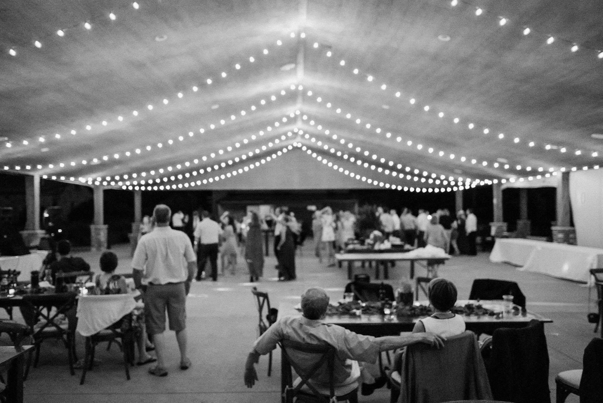 Cafe lights hung in an outdoor pavilion making a roof like shape from the lights