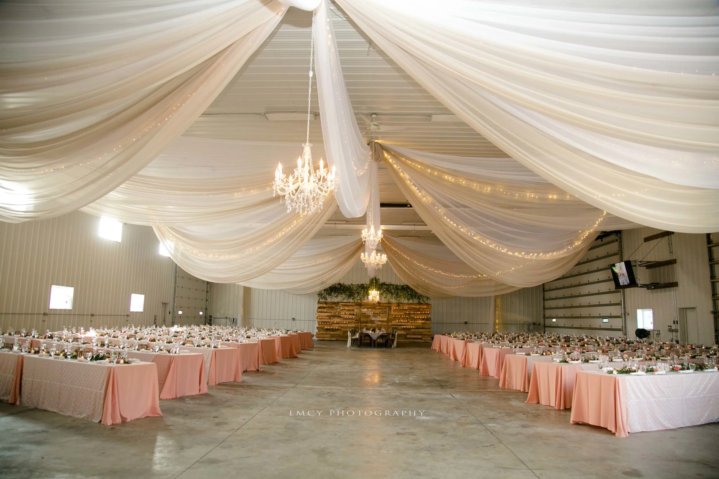 Warehouse reception set up with draping and chandeliers with pink tables and lace overlays