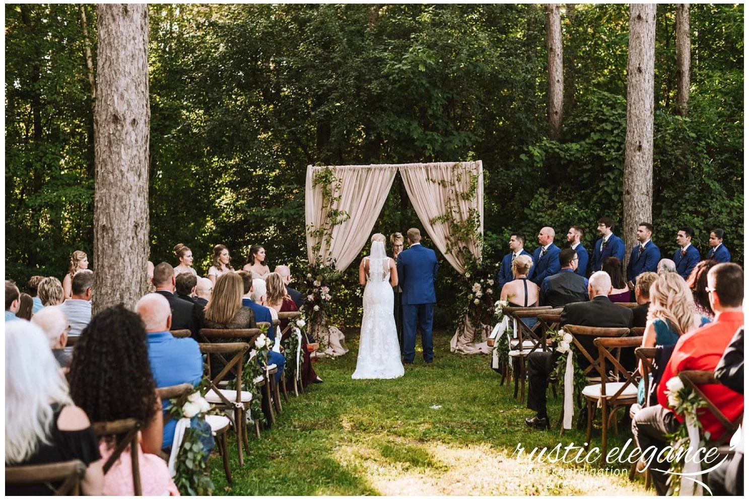 taupe backdrop with greenery for a wedding ceremony in the woods