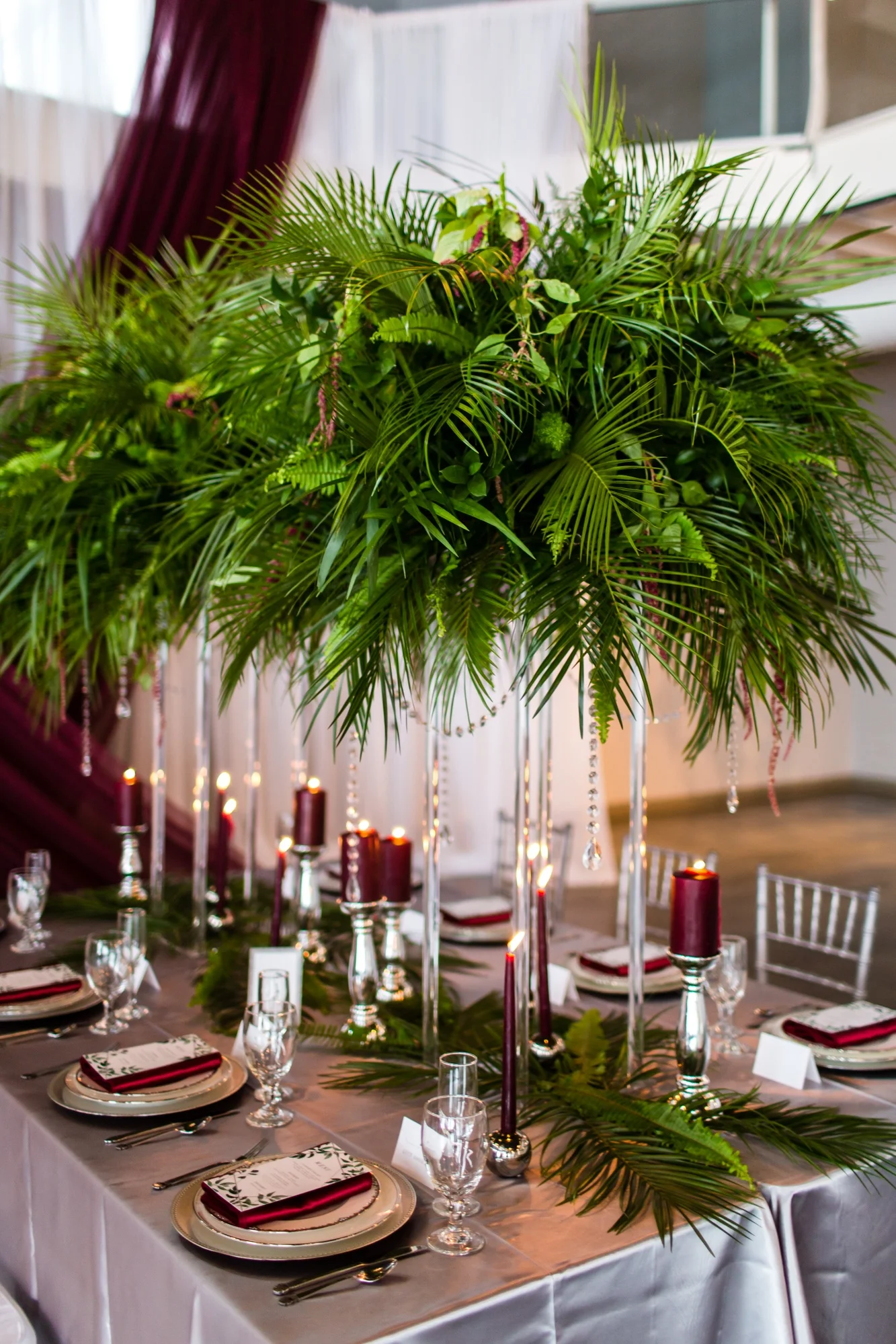 silver satin table linens with fern greenery and burgundy candles