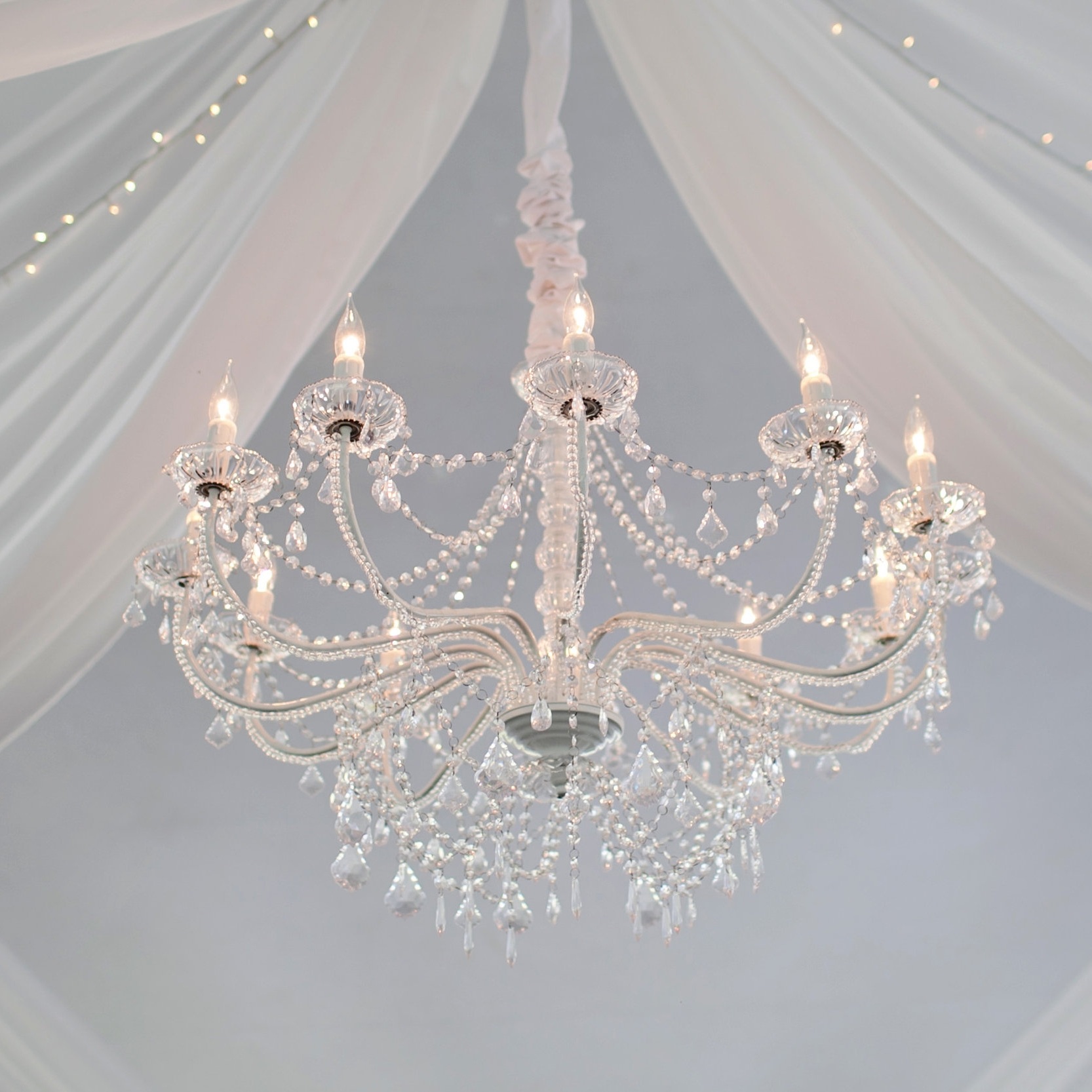 twelve light crystal chandelier hanging with wedding draping