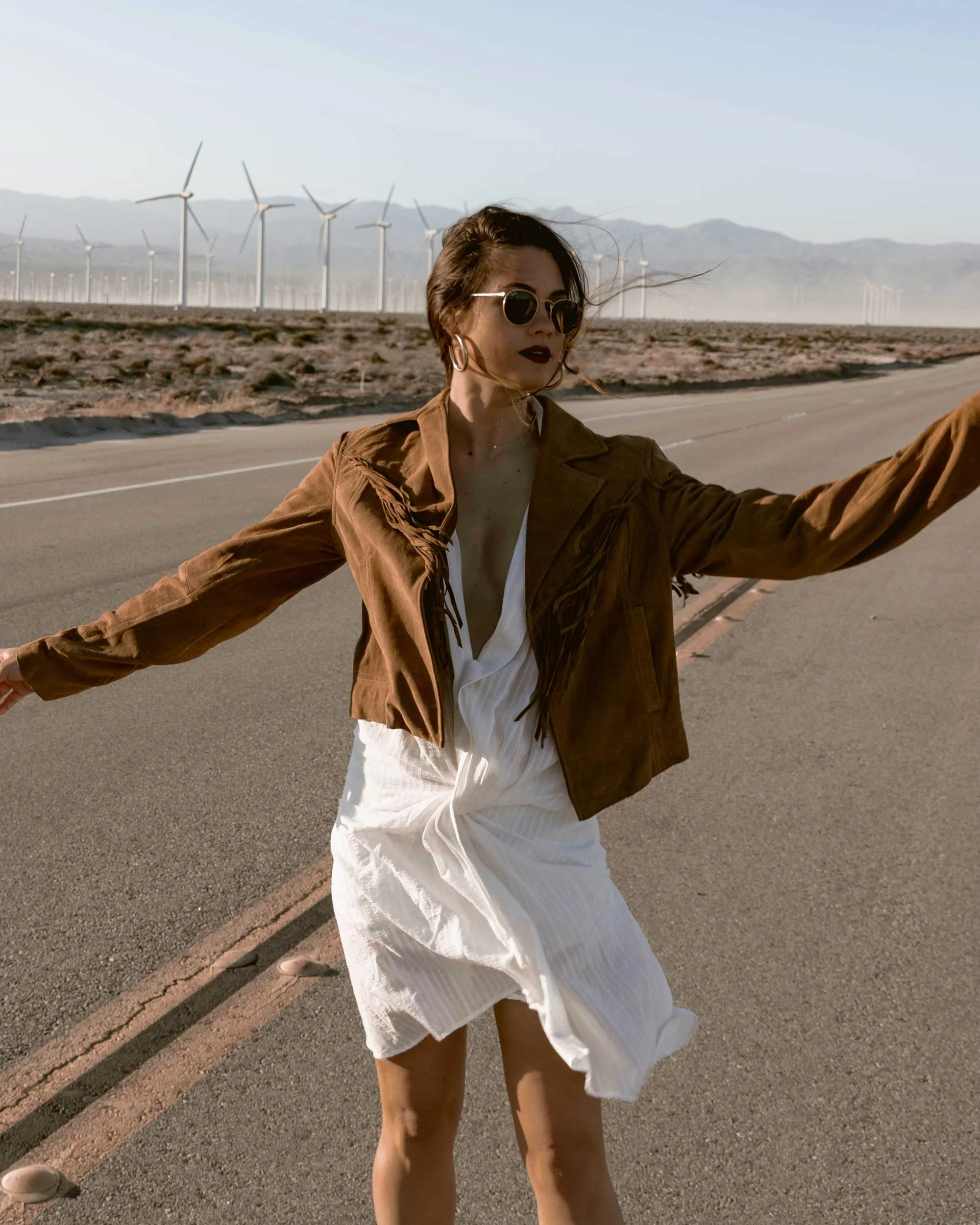 Sarah-Butler-of-Sarah-Styles-Seattle-wears-Jacquemus-Alassio-draped-white-cotton-mini-dress,-Paige-Darlene-Fringed-Suede-Jacket,-and-Paige-suede-western-boot-in-Palm-Springs-for-Coachella-Festival-Outfit-_-@sarahchristine6.jpg