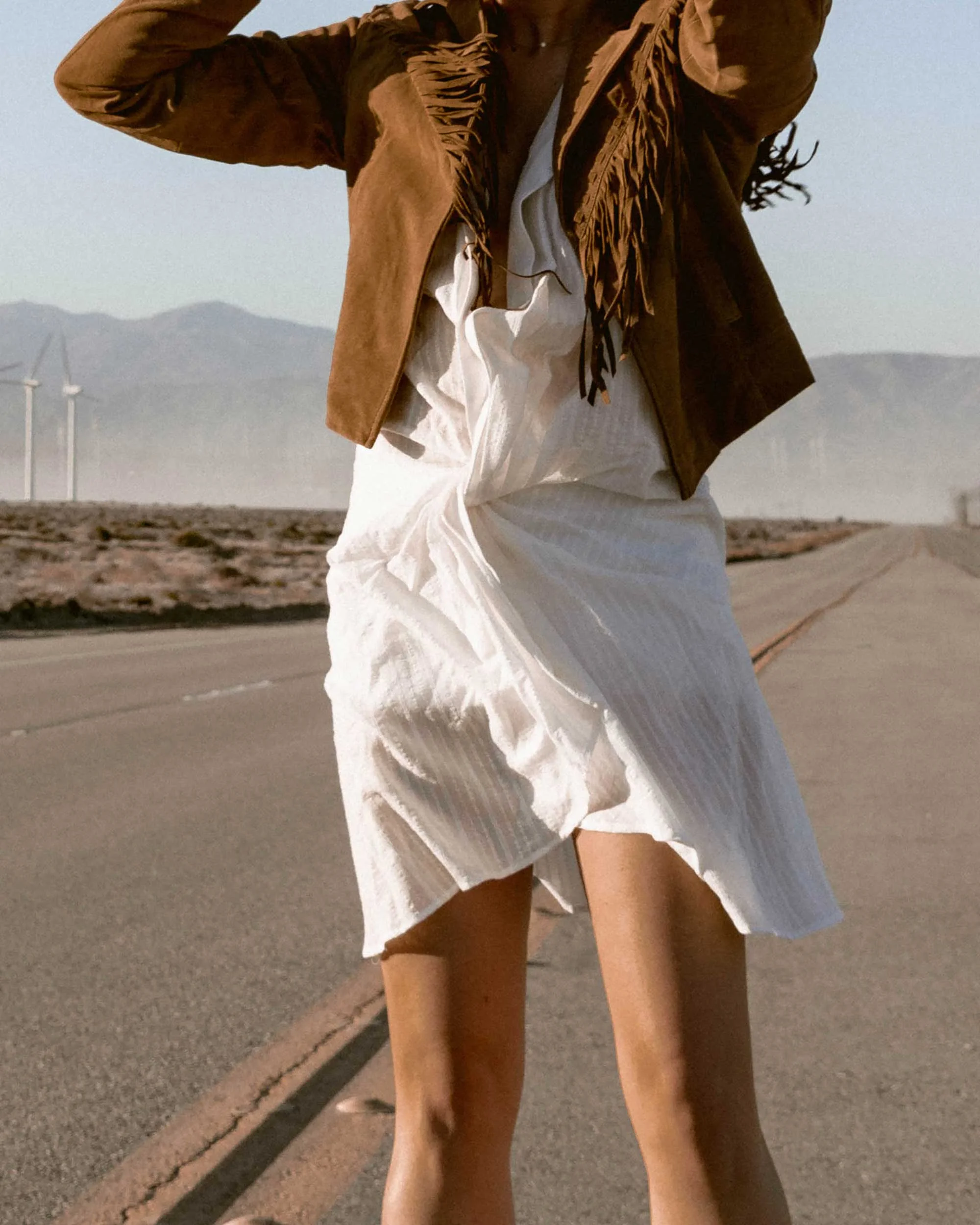 Sarah-Butler-of-Sarah-Styles-Seattle-wears-Jacquemus-Alassio-draped-white-cotton-mini-dress,-Paige-Darlene-Fringed-Suede-Jacket,-and-Paige-suede-western-boot-in-Palm-Springs-for-Coachella-Festival-Outfit-_-@sarahchristine2.jpg