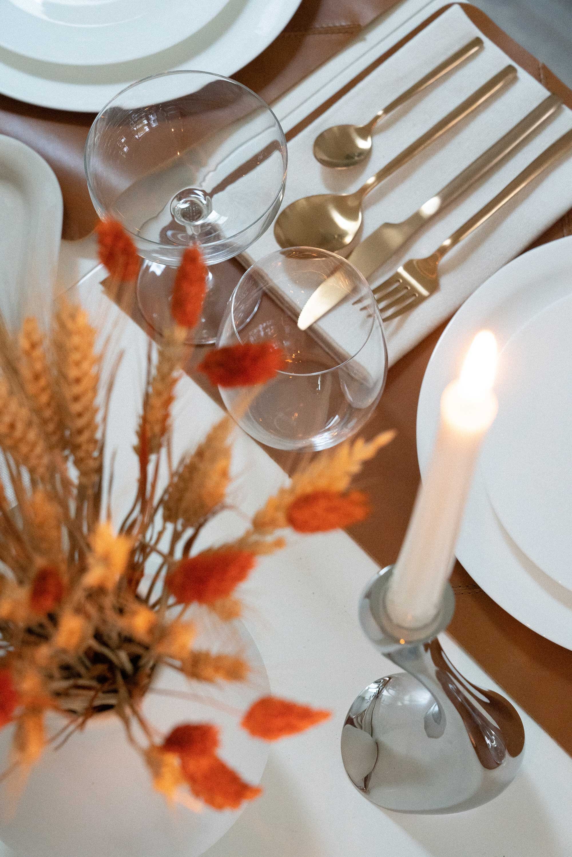 Thanksgiving table settings elegant gold. Sarah Butler of @sarahchristine Thanksgiving table settings featuring Georg Jensen Cobra Candleholder Set, tan leather placemats, and modern gold plated flatware with rustic dried flowers 12.jpg