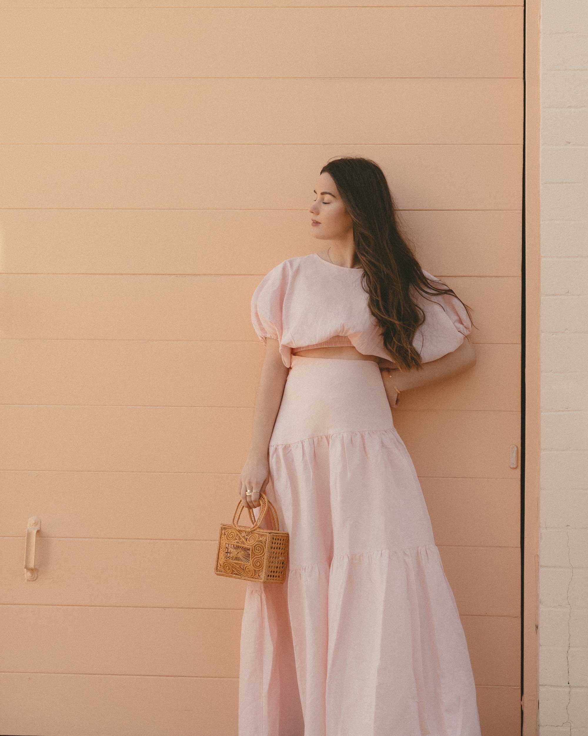 Cute Pink Spring Skirt Outfit Idea. Sarah Butler of @sarahchristine wearing  Mossman Daybreak Pink Linen Crop Top and Pink Linen Asymmetrical Tiered Skirt in Newport Beach, California - 5.jpg