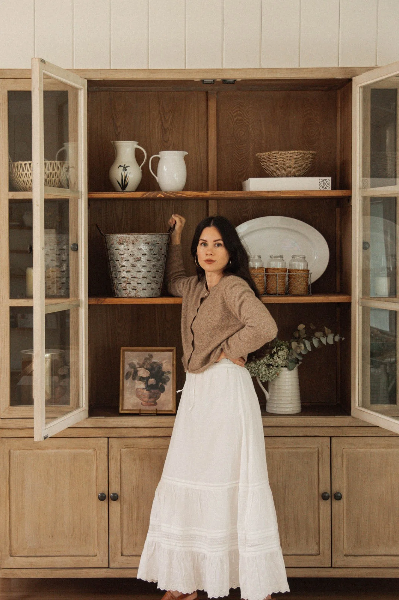 white midi skirt neutral outfit in front of styled wood cabinet