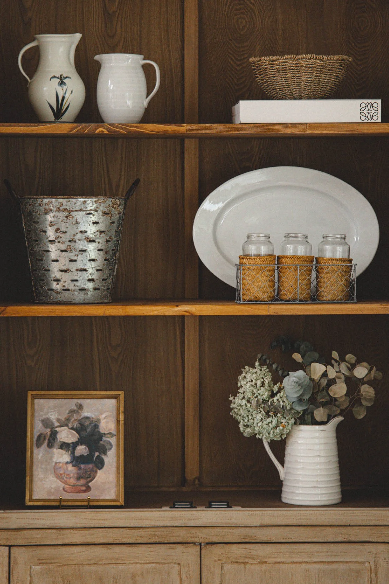 modern rustic cabinet shelf styling with white ceramics and woven baskets
