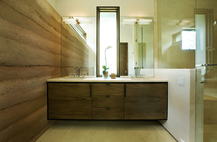 Natural stone slab wall is a showcase piece in this master bath with floating sink base.