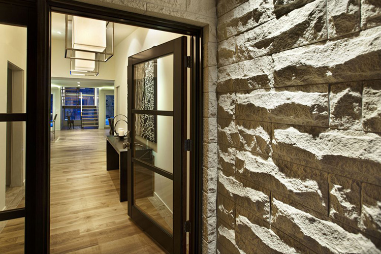  Dramatic shadows are created on this rough stone wall as you enter the home. 