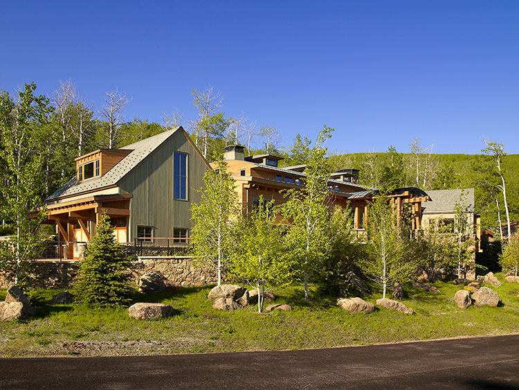  Modern home with natural wood exterior, exposed beams and natural stone retaining walls against the hillside of Snowmass Village, Colorado  