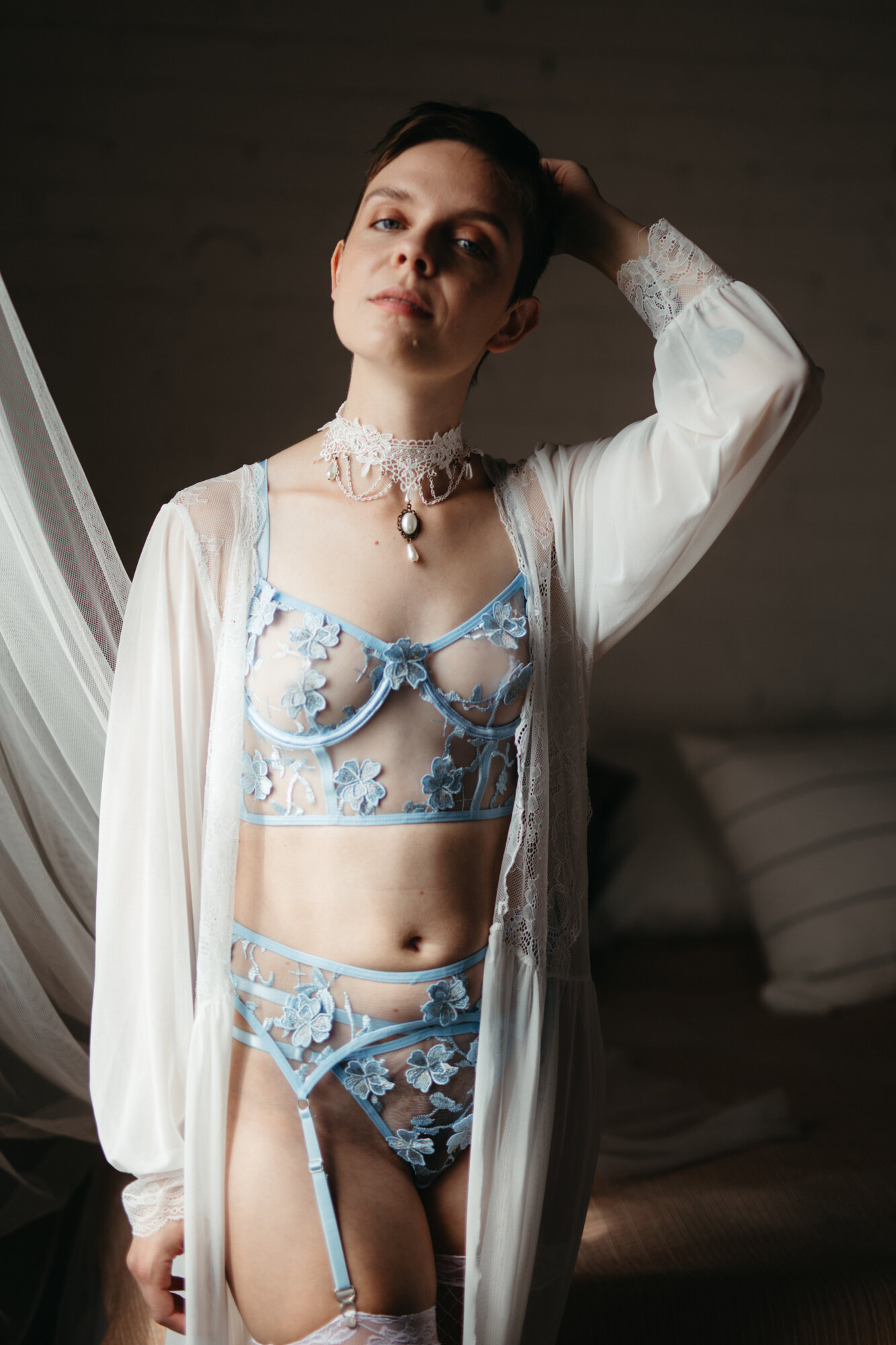 Genderqueer person wearing victorian style blue lingerie and a white robe
