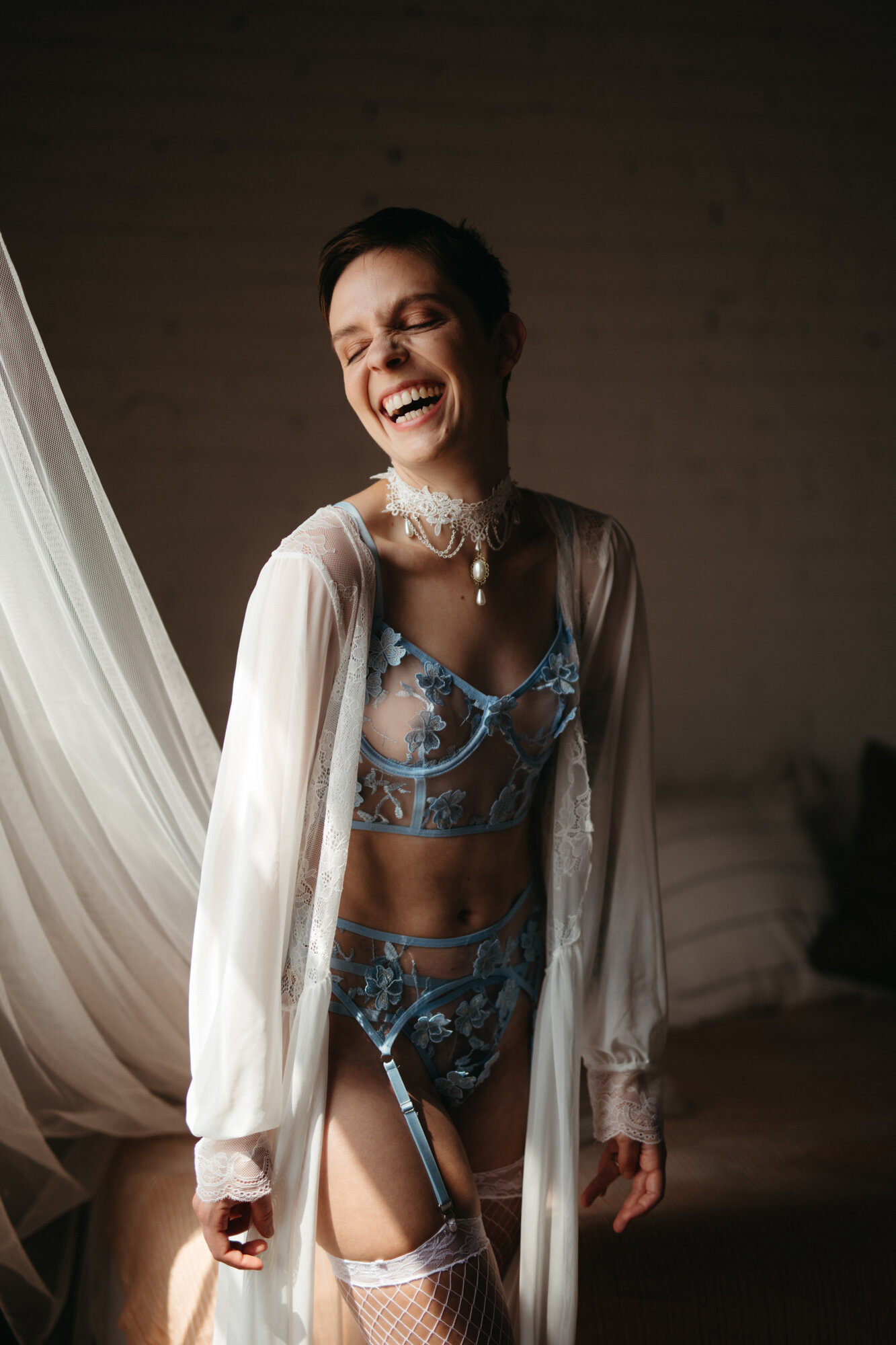Genderqueer person a blue lingerie set and laughing
