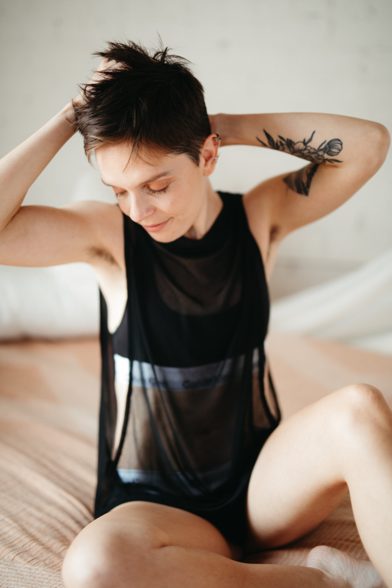 Genderqueer masculine boudoir photo of person with short hair with both hands behind their head