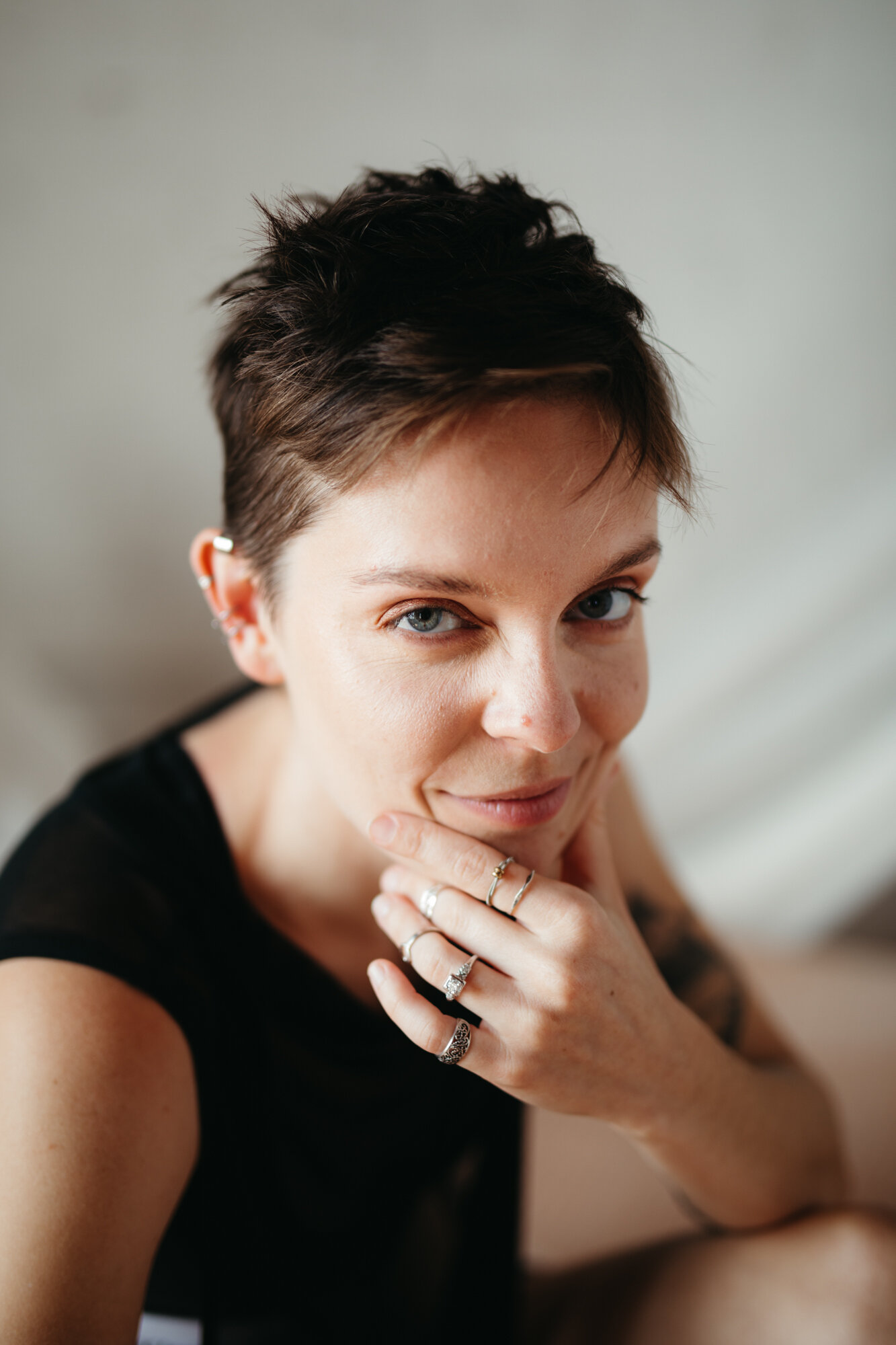 Queer boudoir photo of person with short hair smirking