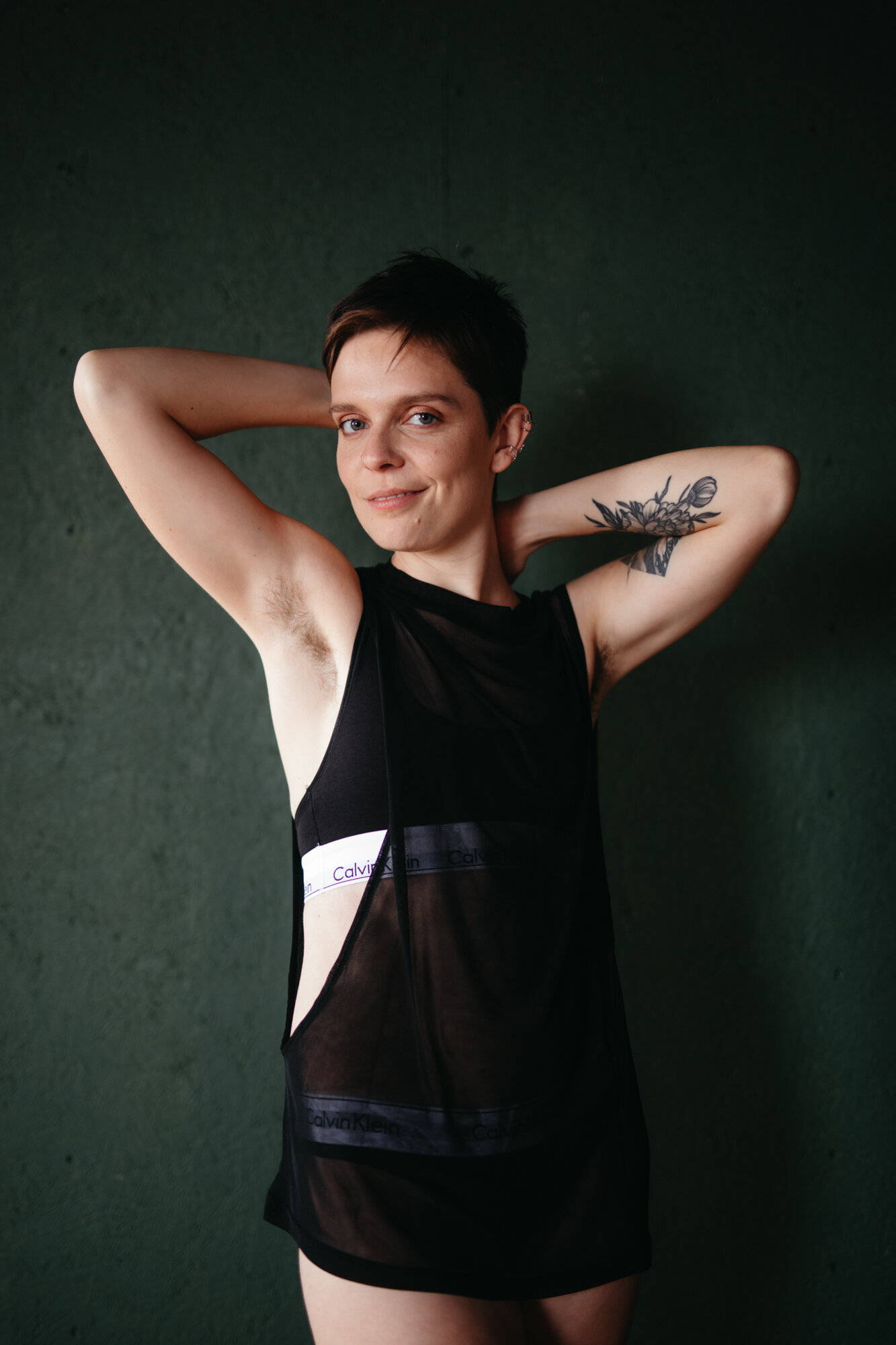 Genderqueer masculine boudoir photo of person flexing their arm muscles