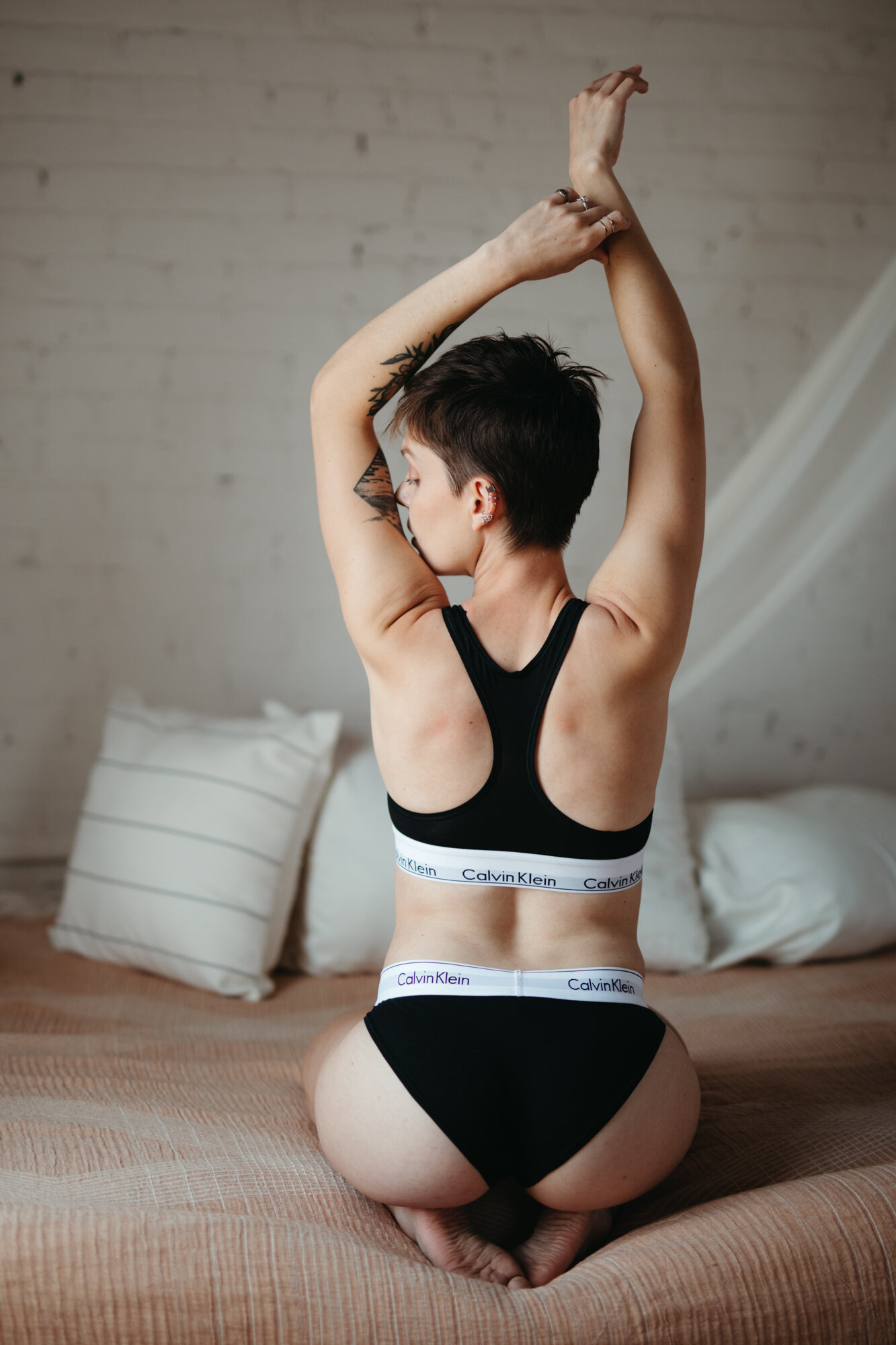 Queer boudoir behind view photo of someone stretching wearing a Calvin Klein underwear set 
