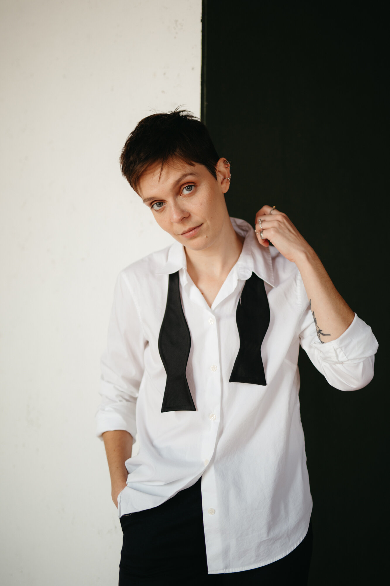 Genderqueer boudoir photo of person wearing a white dress shirt with open bowtie looking at camera