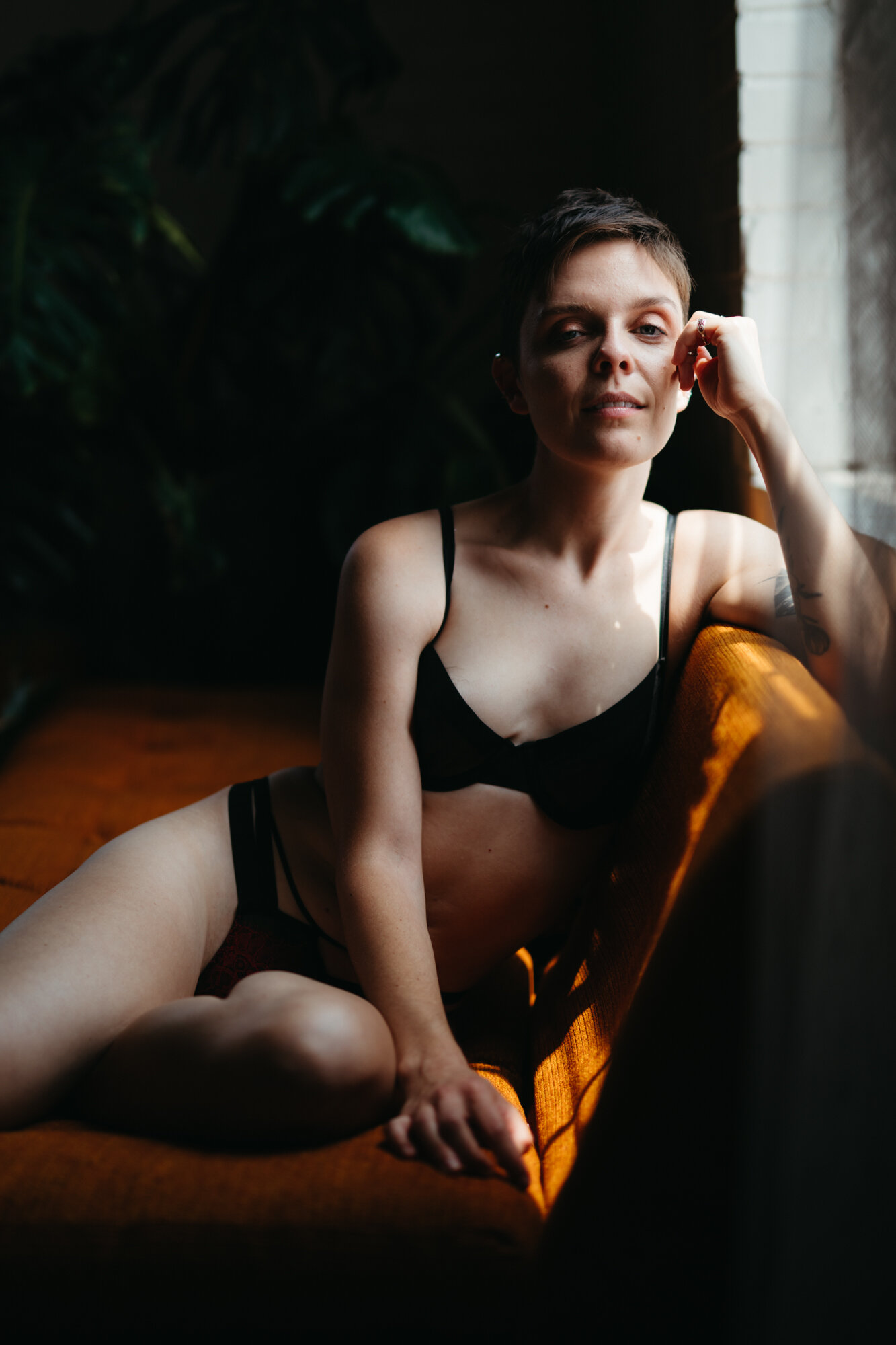 Genderqueer boudoir portrait of person with masculine energy wearing feminine lingerie