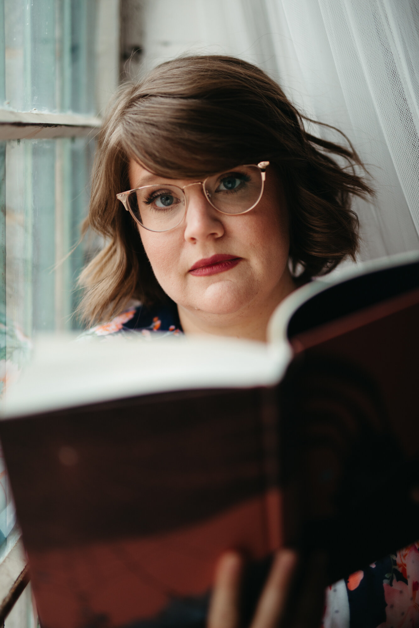 Boudoir portrait of person sitting in window reading a book