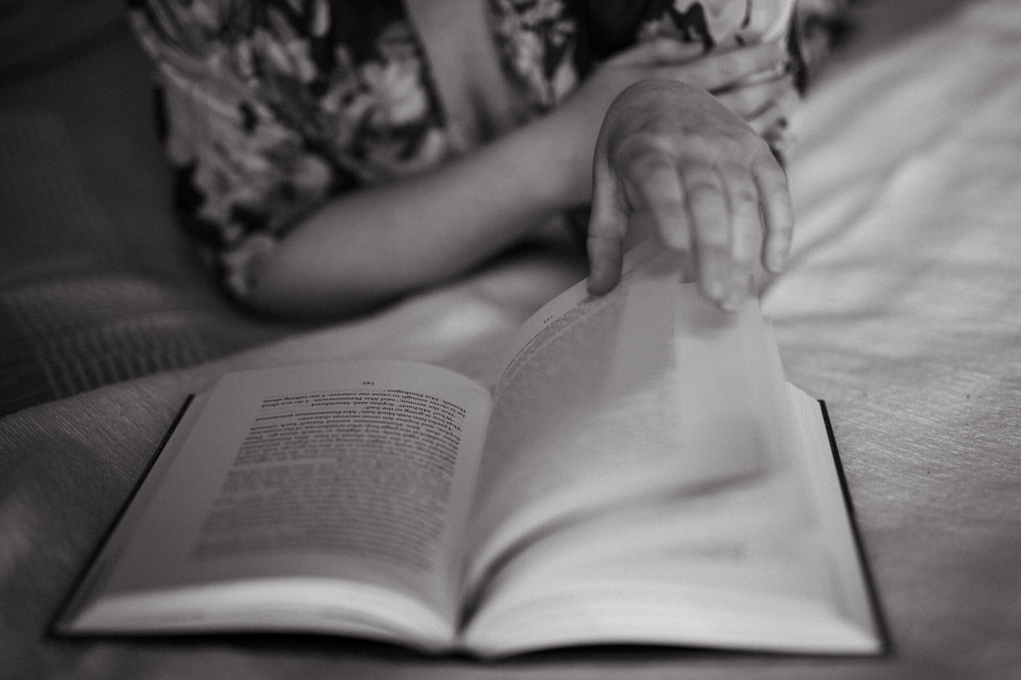 black and white photo of hands and pages of book being turned