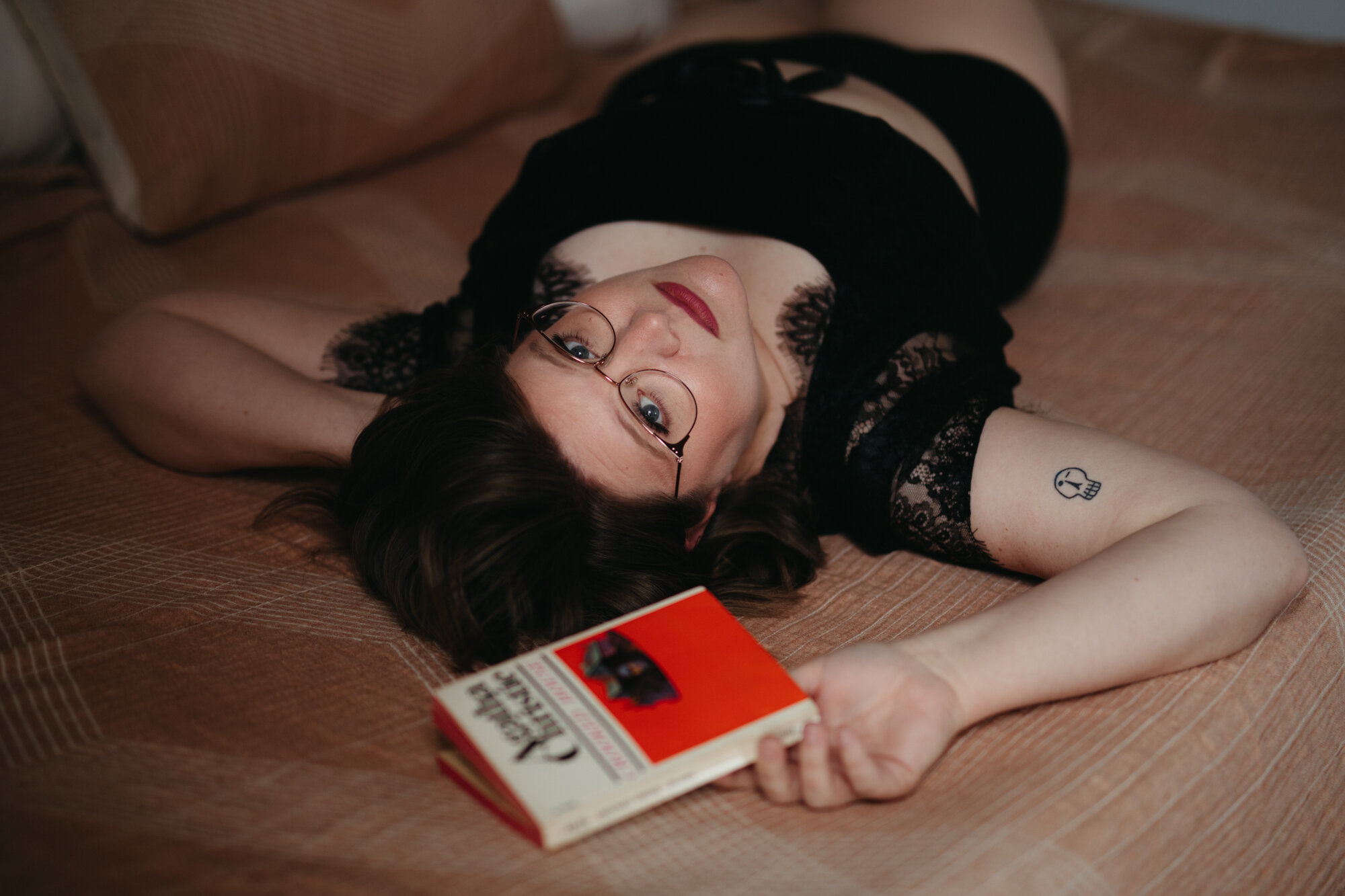 asexual boudoir portrait of librarian laying on bed with book in their hands