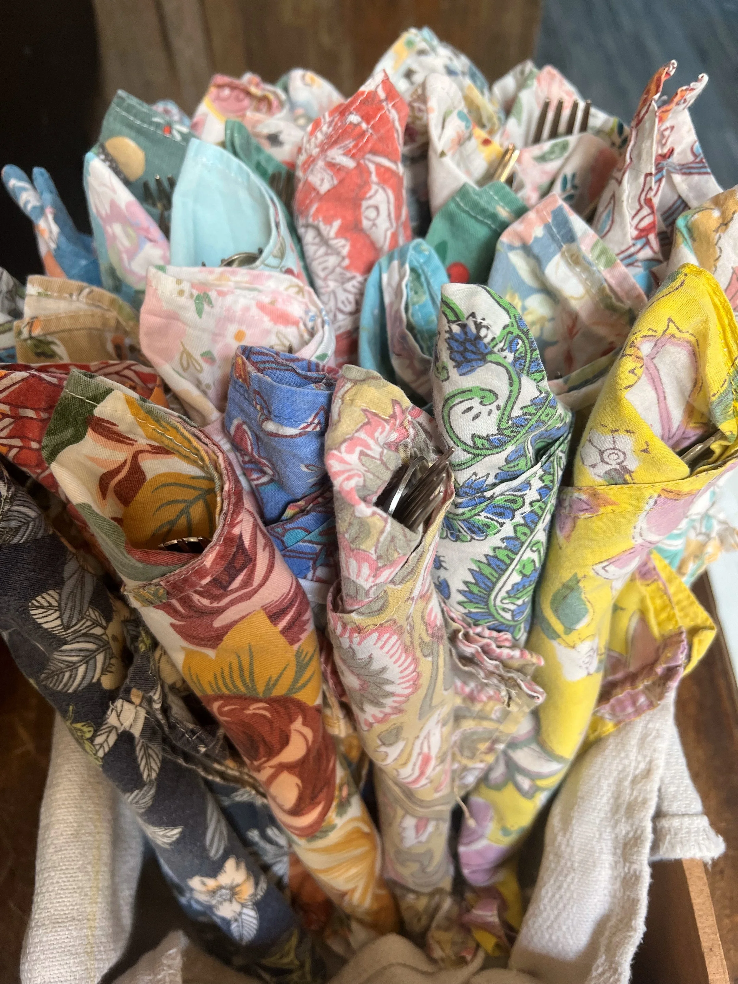 A collection of colorful fabric scraps with various patterns, some conjoined with metal clips, laid on a surface covered with a white textured cloth.