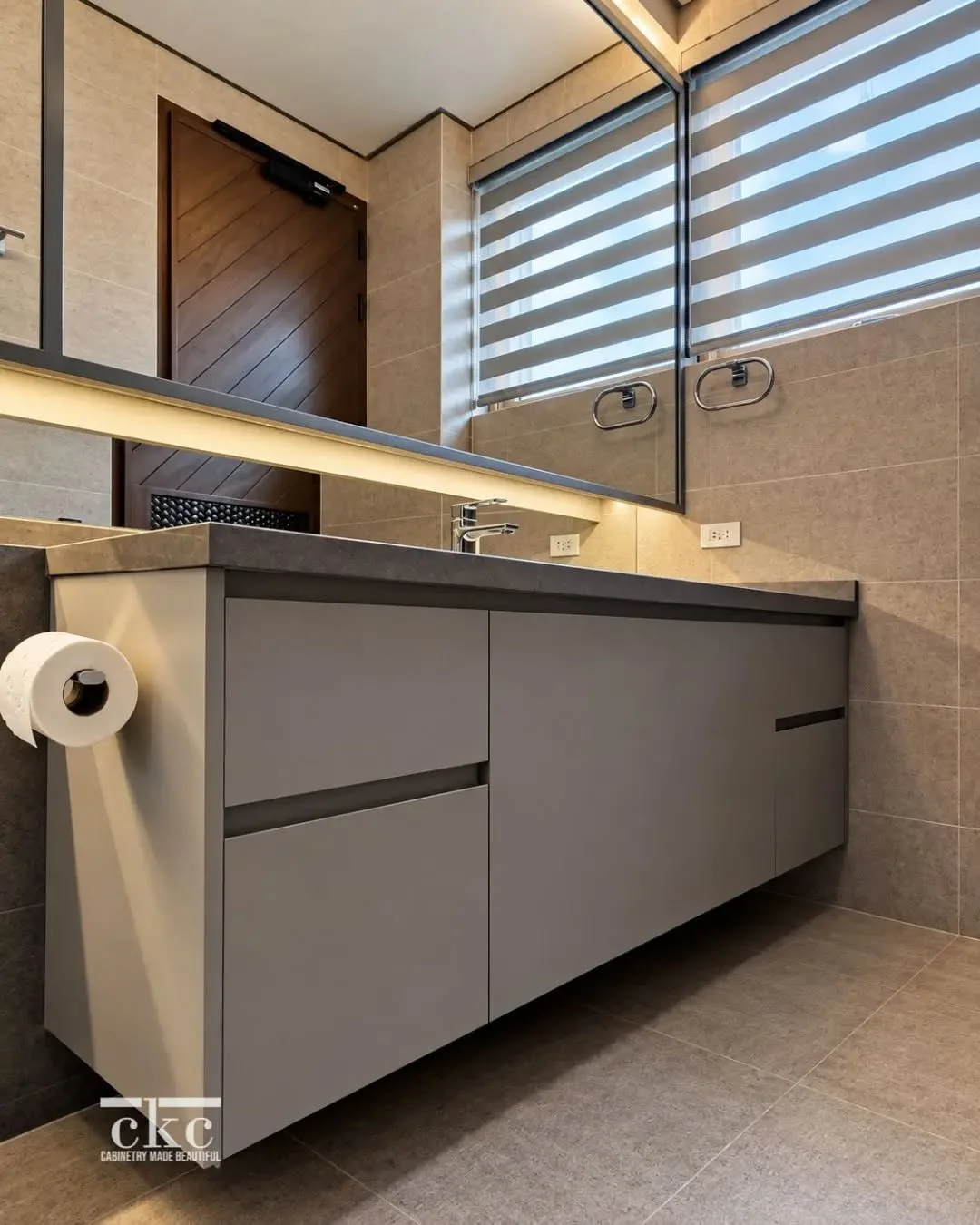 A floating vanity keeps the bathroom feeling open and uncluttered, while custom cabinetry provides ample storage without taking up visual space.

We love how the muted grey finish works with the stone countertop and warm lighting for a clean, underst