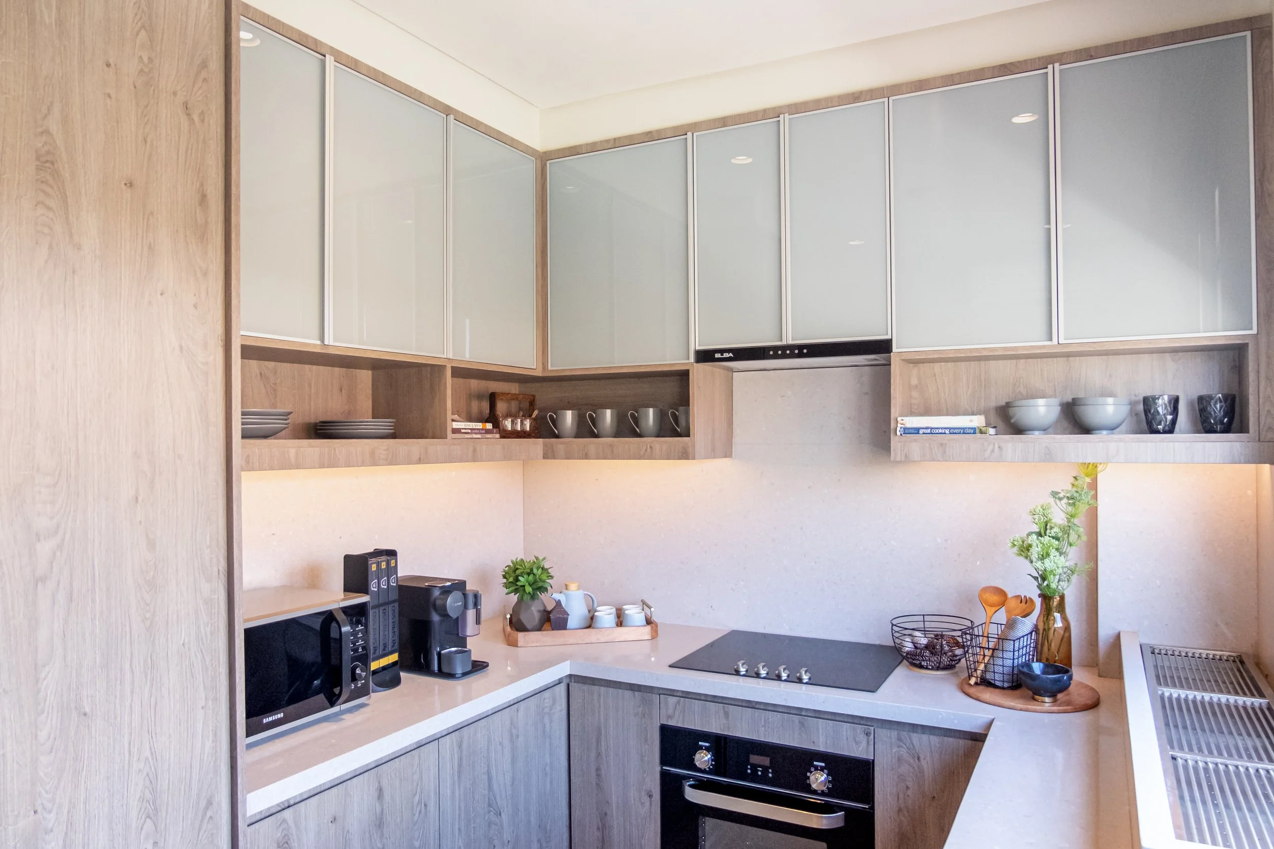 Modern semi-custom modular kitchen cabinets with wood grain finishes and integrated appliances in a Makati City home.