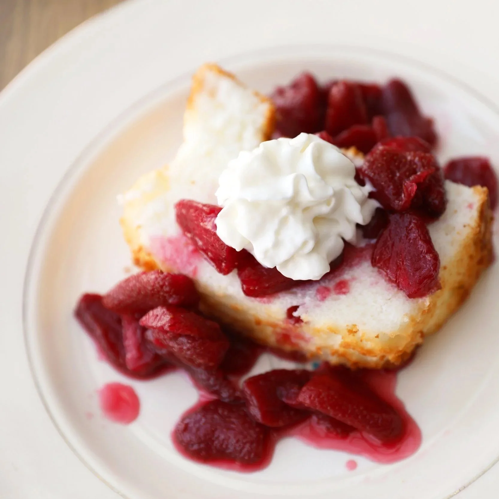 Slice of angel food cake with a strawberry topping and whipping cream