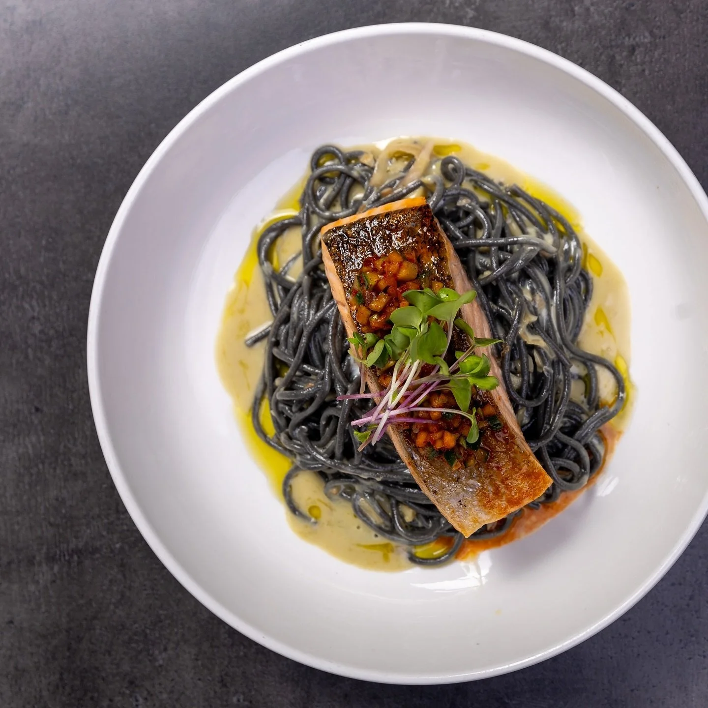 Crispy salmon with a kick of wasabi beurre blanc, over a bed of squid ink pasta, topped with fresh apple-cucumber relish.