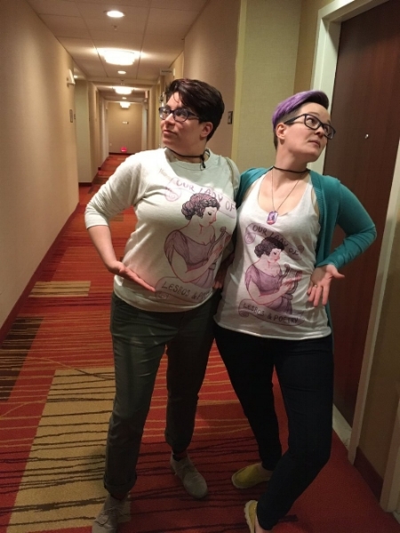 Your totally gay and totally nerdy hosts wearing their matching Sappho "Our Lady of Lesbos & Poetry" gear that they totally didn't just buy for the express purpose of showing them off in their panel nope