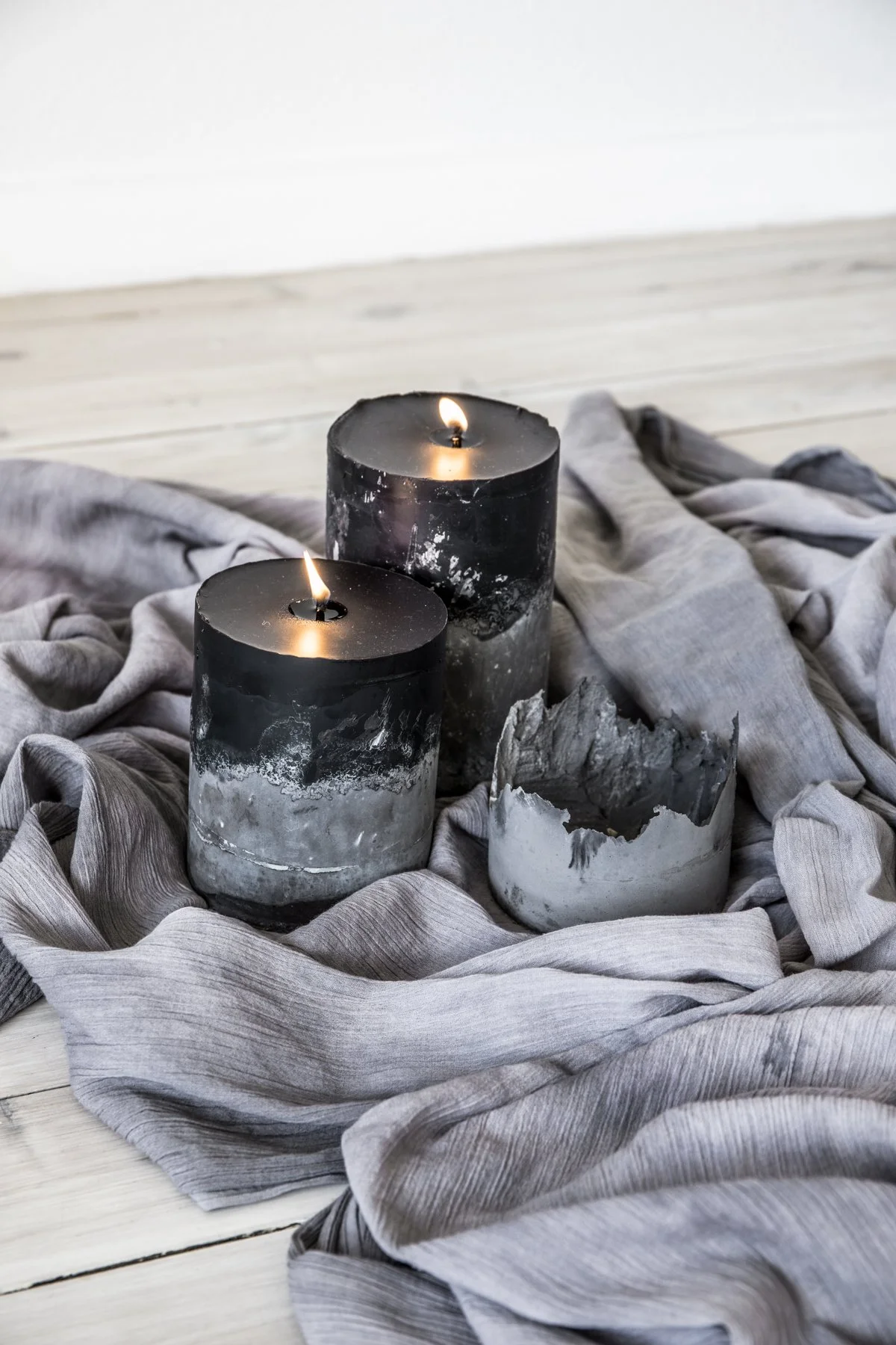 Three black and gray candles on a gray fabric