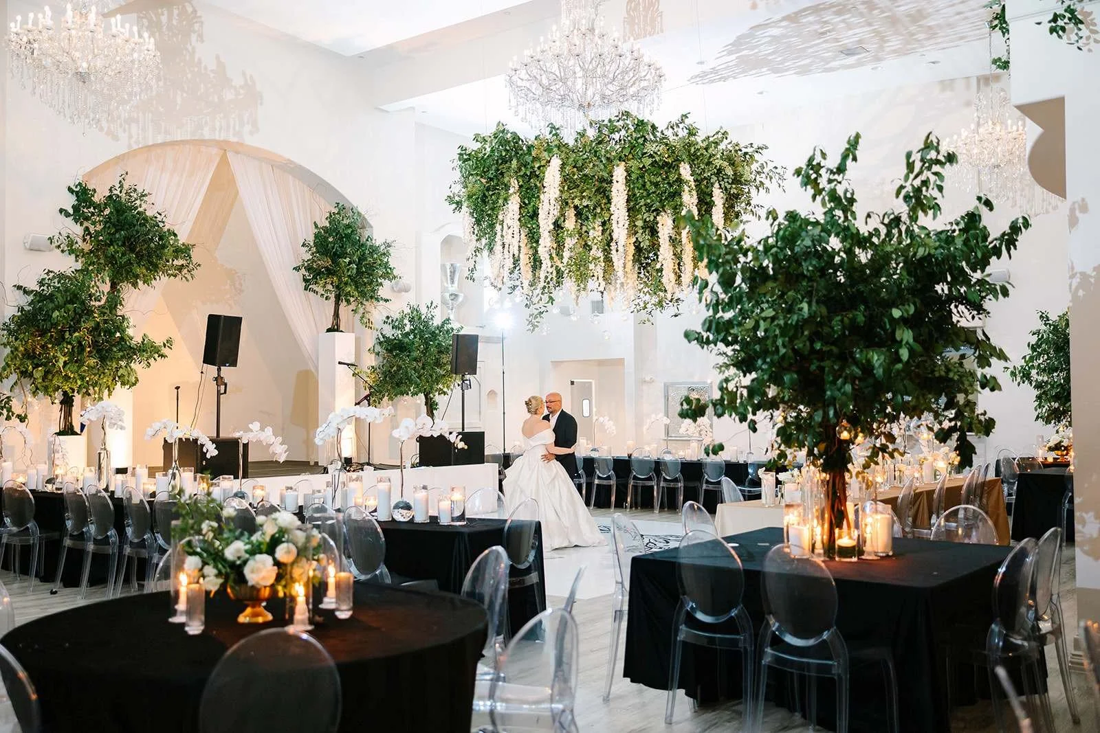 Stunning wedding reception at Knotting Hill Place showing bride and groom, elaborate  white floral chandelier installation, elegant table settings, centerpieces, reception  setup, chandeliers, and full-service ballroom atmosphere for 300-400 guests