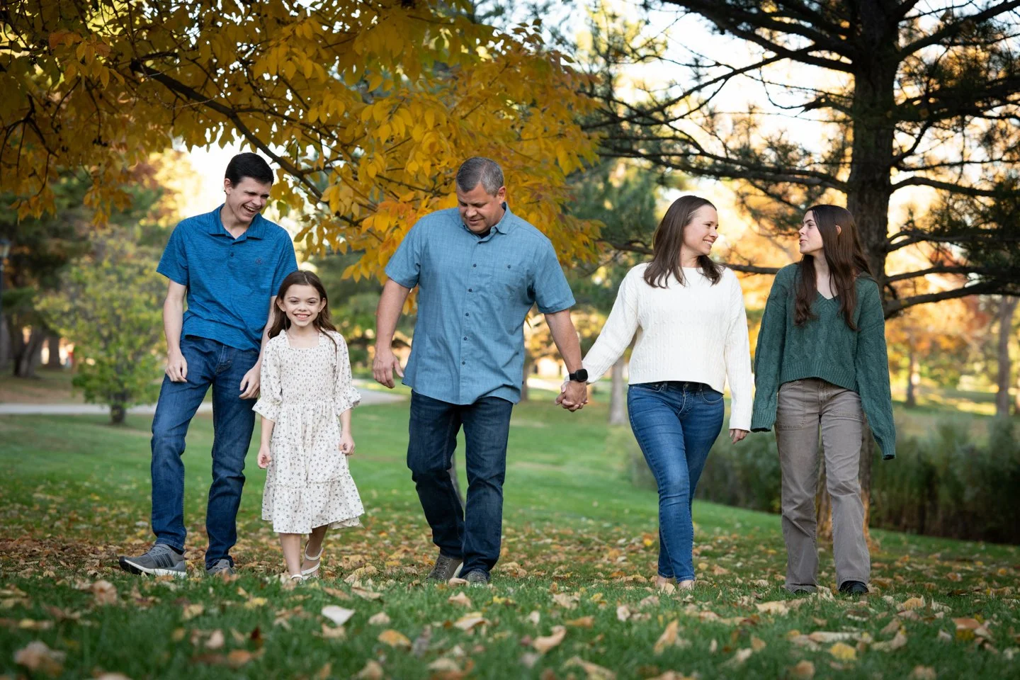 Family of five walking together beneath colorful fall trees during a family mini session in Ken Caryl, Colorado