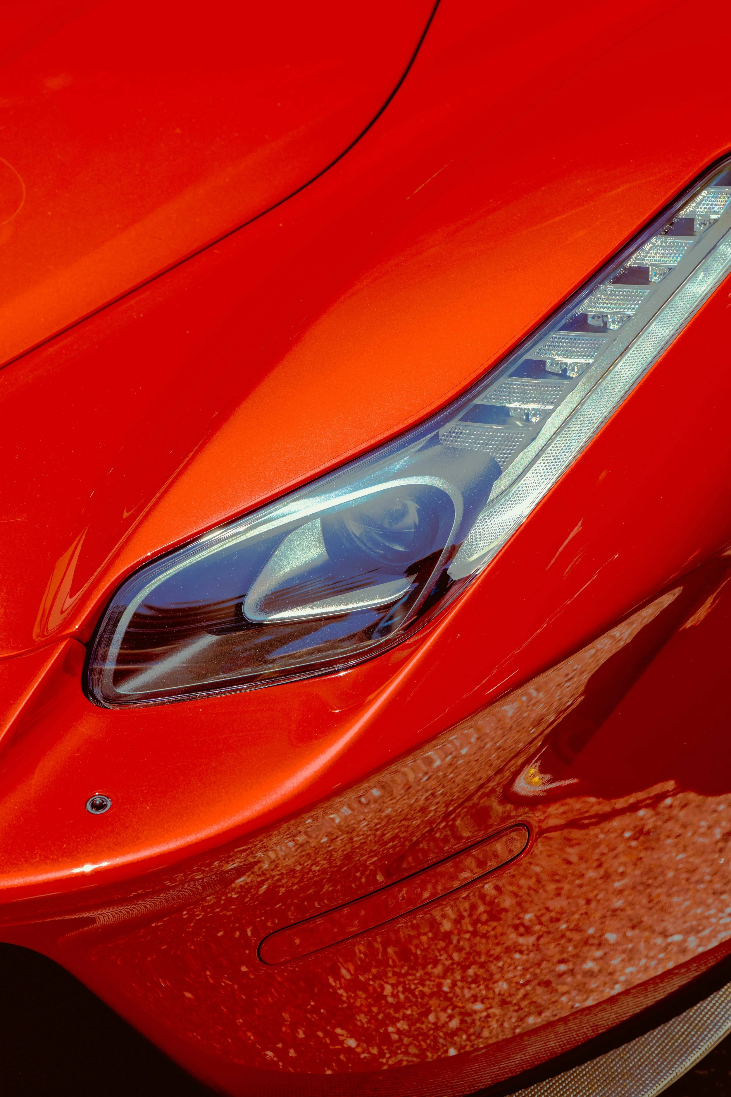Close-up of a red car's headlight and front fender.