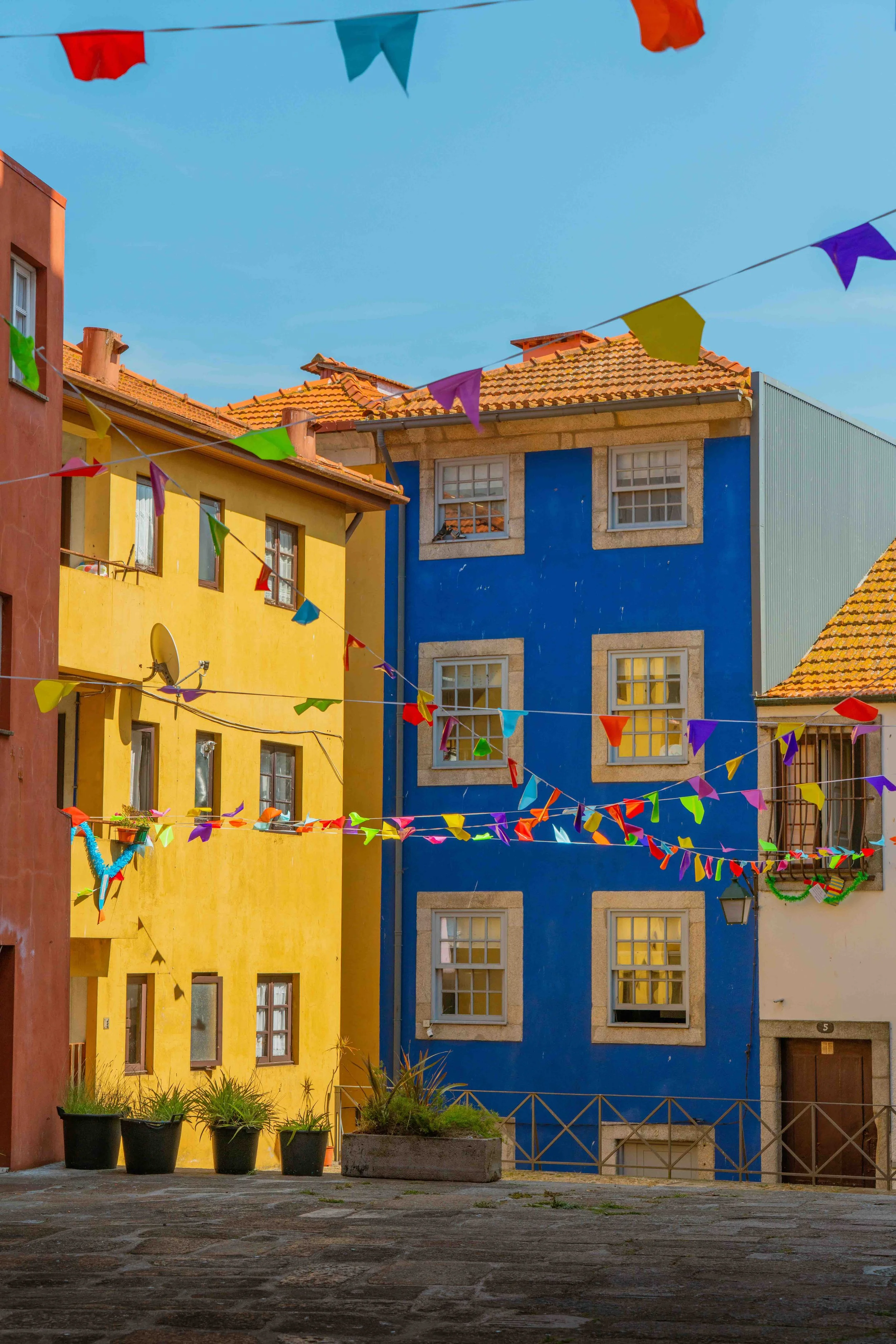 Colorful buildings painted in yellow and blue with festive flags strung across the courtyard.