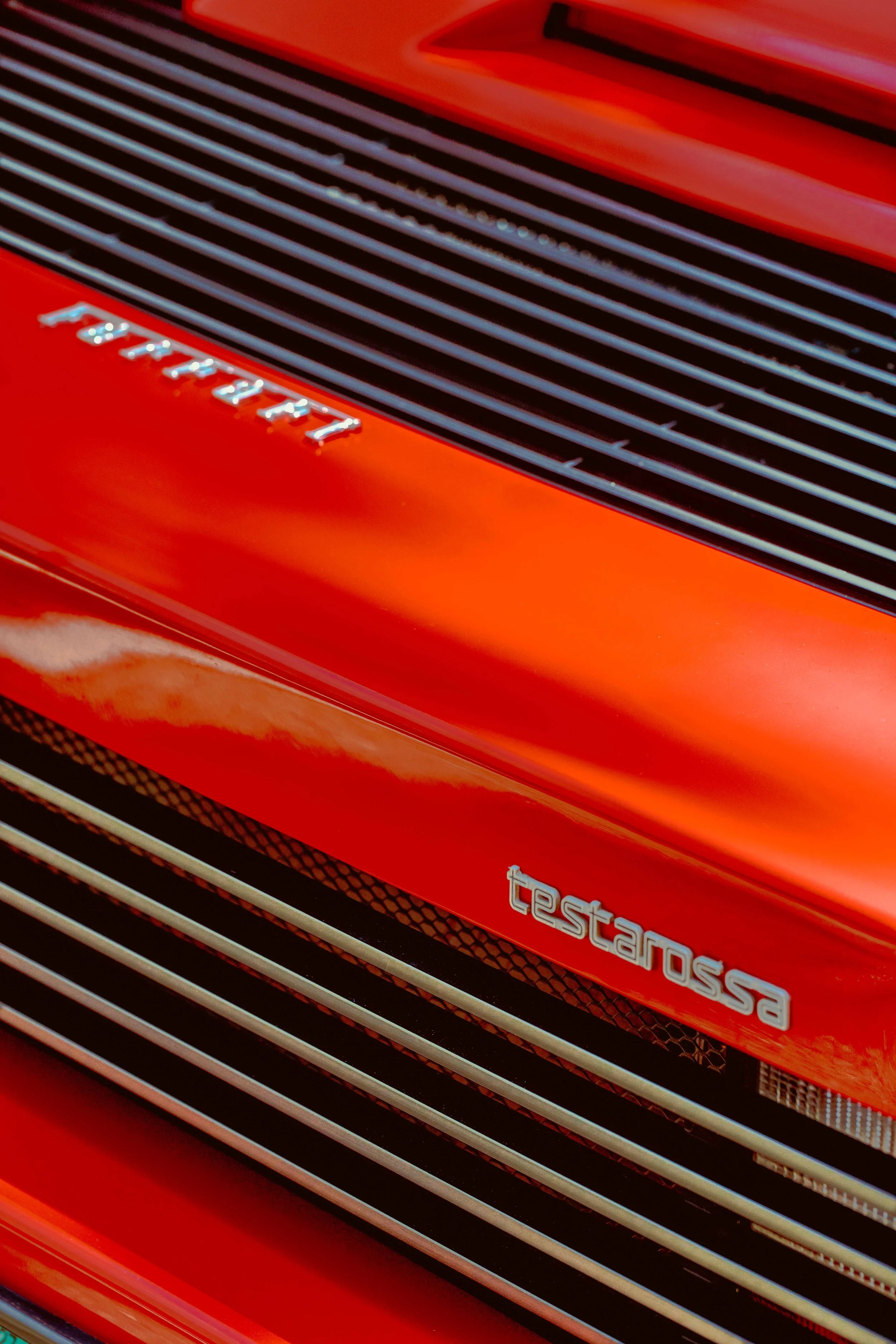 Close-up of a red Ferrari Testarossa with silver lines and badging.