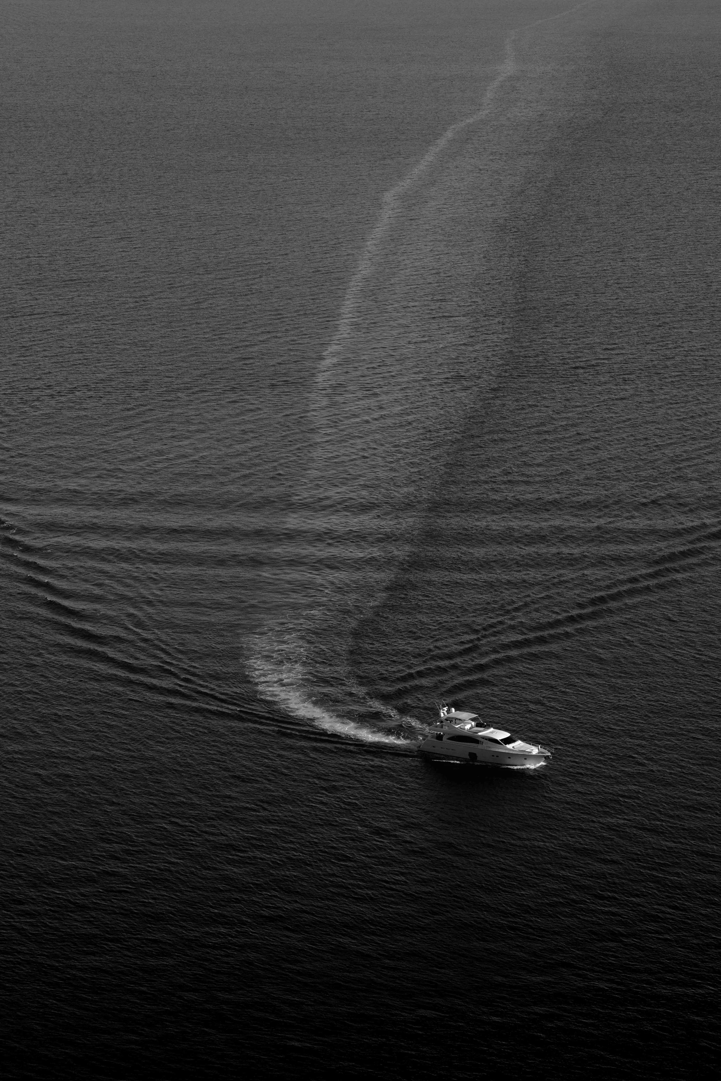 A yacht cruising through open water, creating a trail in its wake.
