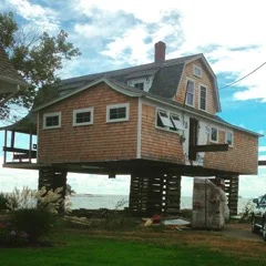 The house rested on wooden cradles in order to drill into the rock to create the metal posts which cement is poured over 