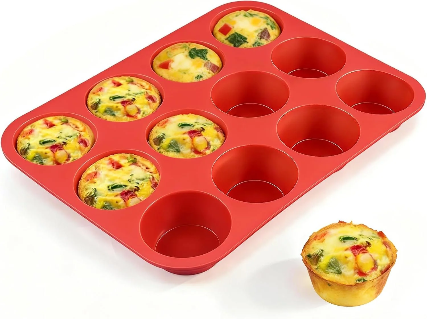 A red silicone muffin pan filled with six mini egg muffins with vegetables next to an empty muffin slot.