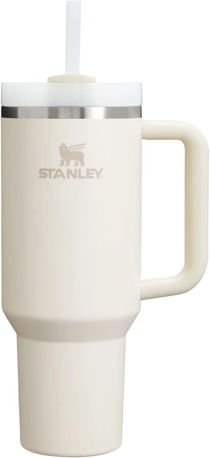 A white Stanley travel mug with a handle and a lid with a straw, designed for drinking beverages on the go.