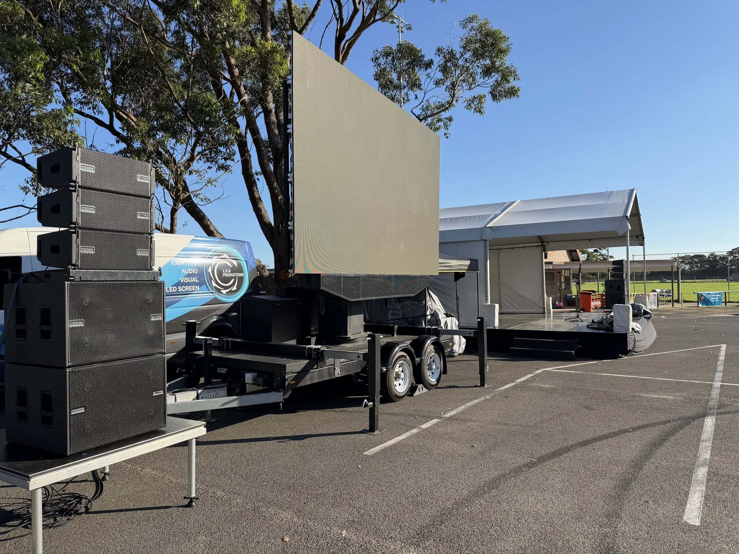 LKR LED screen trailer and line array PA set up beside a stage at an outdoor community event in Sydney